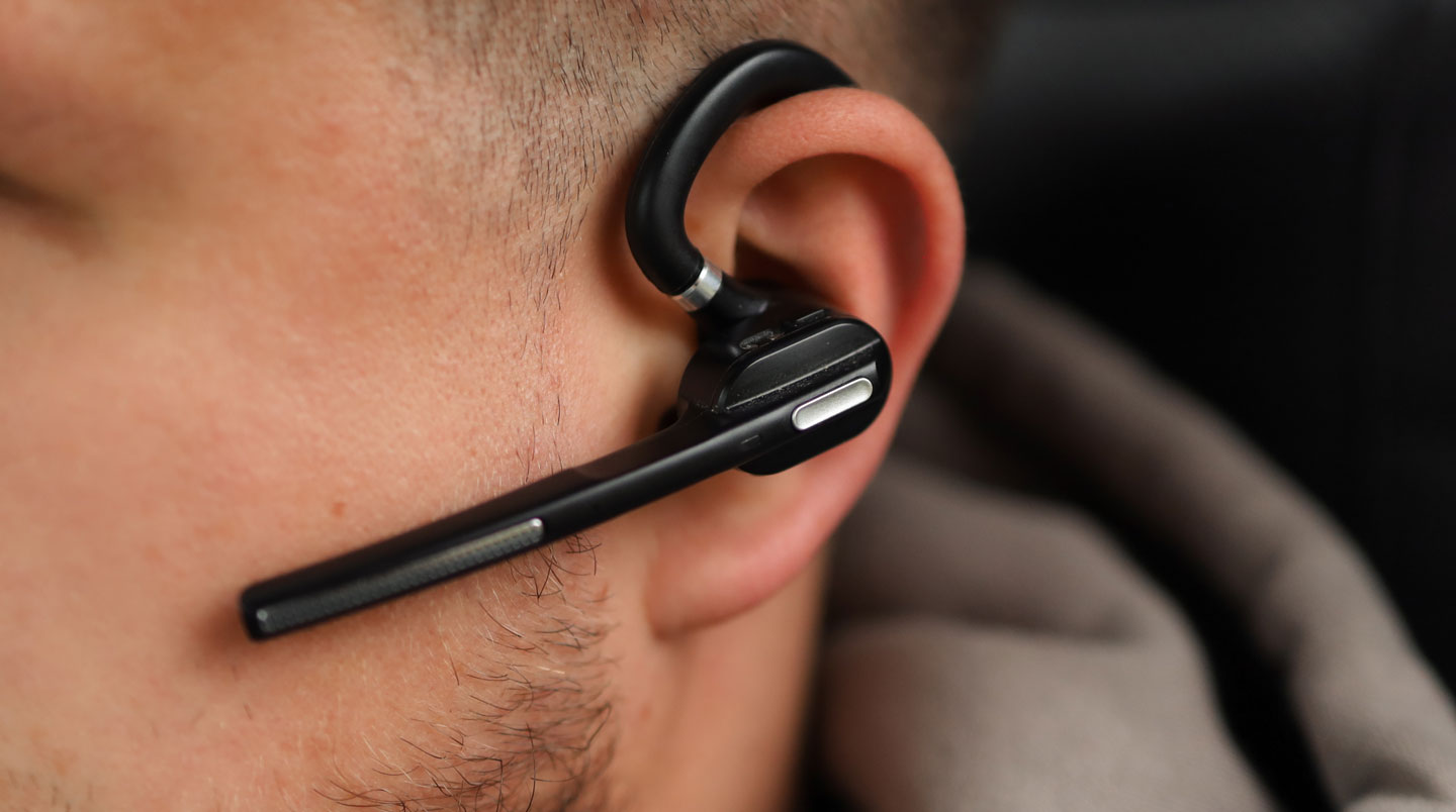 Smartphone posé sur un bureau avec des écouteurs filaires branchés illustrant l